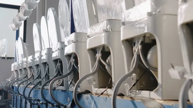 Assembled toilets connected to hoses and cables along a factory test line